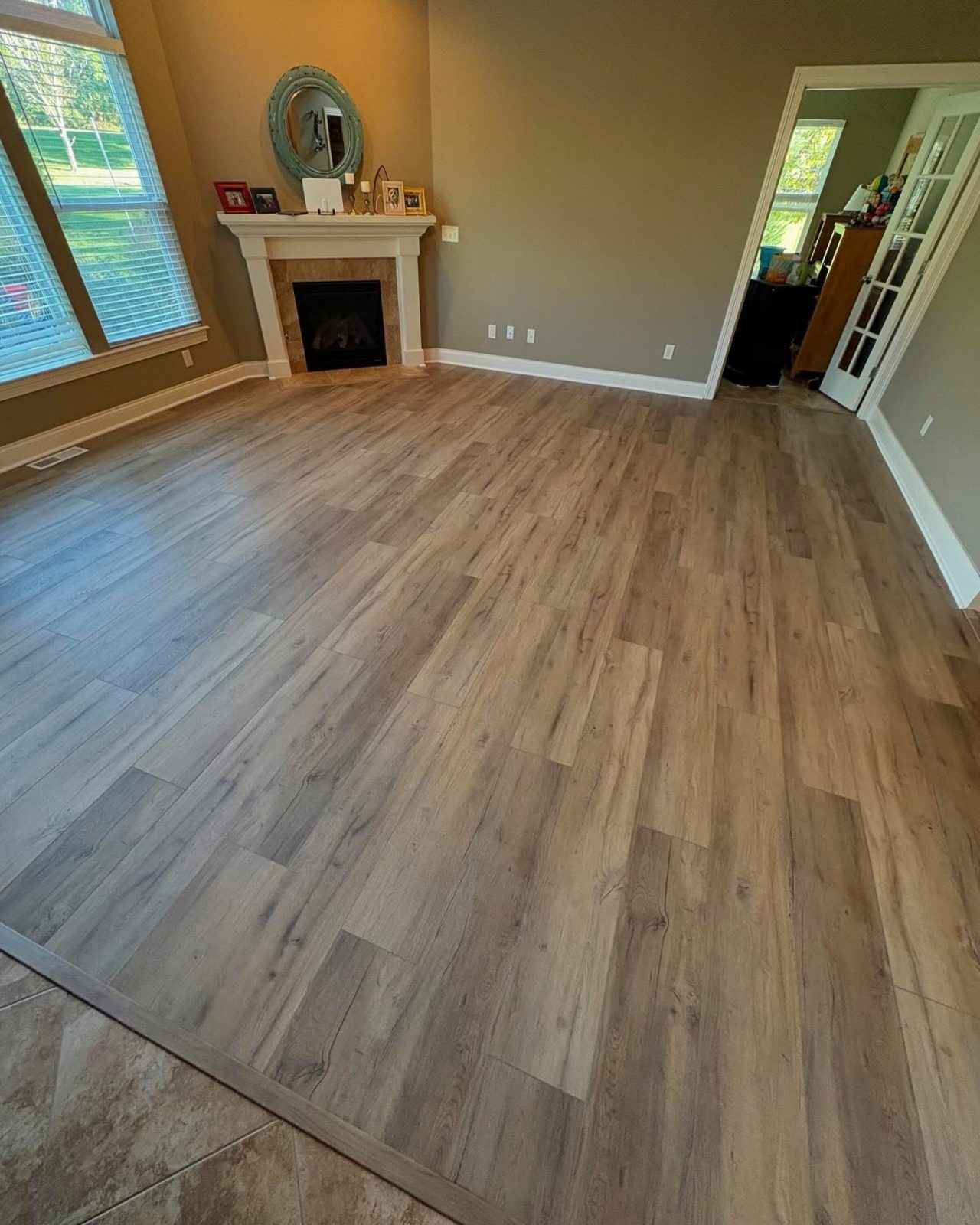 Gray-toned LVP flooring in a Kettering, OH living room with a stone fireplace